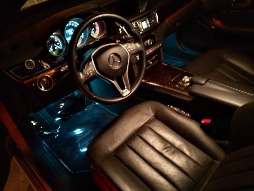 Luxurious black leather interior of a car with illuminated dashboard, steering wheel, and center console.